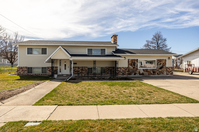 306 West 725 North Logan, UT 84321 - Photo 1 of 1 View of front facade featuring a chimney, a porch, brick siding, and a front yard