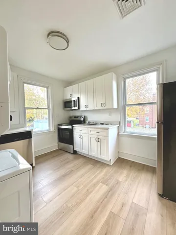 a kitchen with a white cabinets and wooden floor