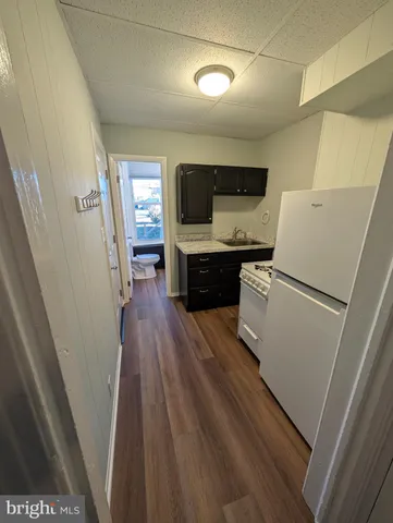 a kitchen with sink a refrigerator and wooden floor