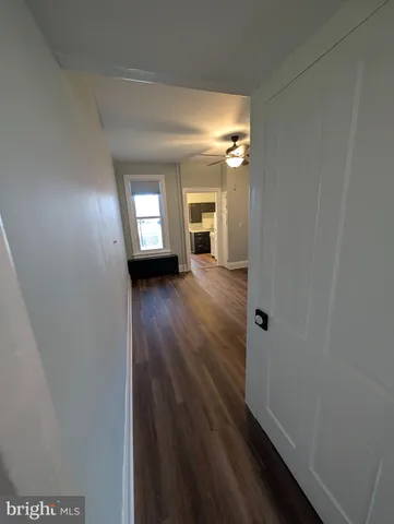 a view of a hallway with wooden floor and a living room