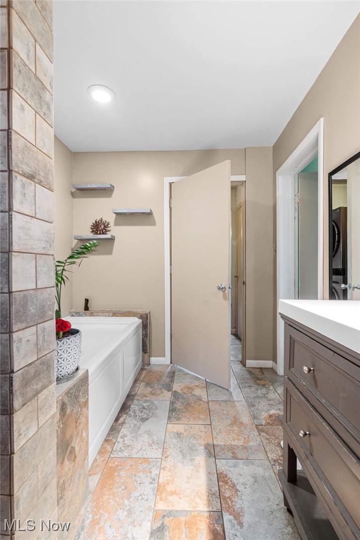 10228 Beloit Snodes Road North Benton, OH 44449 - Photo 15 of 25 Full bathroom with vanity, a garden tub, and stone finish floors