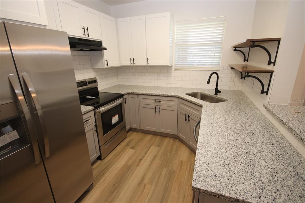 1575 Blue Magnolia Road Brandon, FL 33510 - Photo 9 of 22 a kitchen with stainless steel appliances granite countertop a sink stove and refrigerator