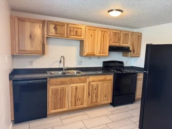 a kitchen with granite countertop a sink dishwasher stove and cabinets