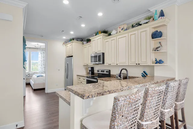 a kitchen with stainless steel appliances granite countertop a refrigerator a stove a sink and white cabinets with wooden floor