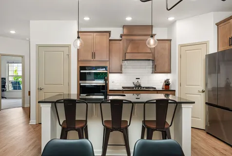 a kitchen with stainless steel appliances granite countertop a stove top oven a refrigerator a sink and white cabinets with wooden floor