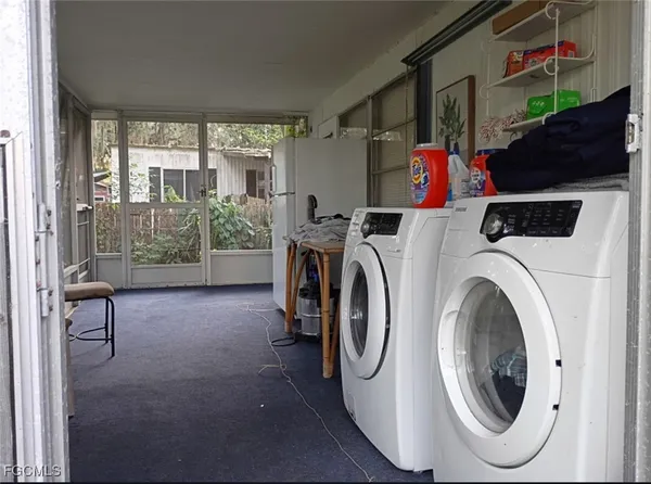 a utility room with dryer washer and a view of living room