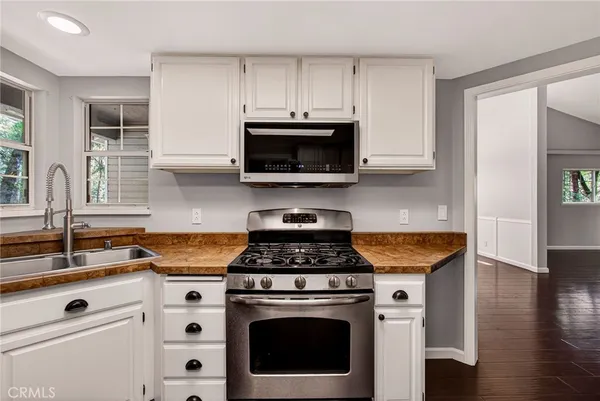 a kitchen with a refrigerator a stove a sink wooden floor and cabinets