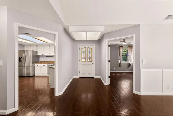 a hallway with wooden floor on wall and a kitchen