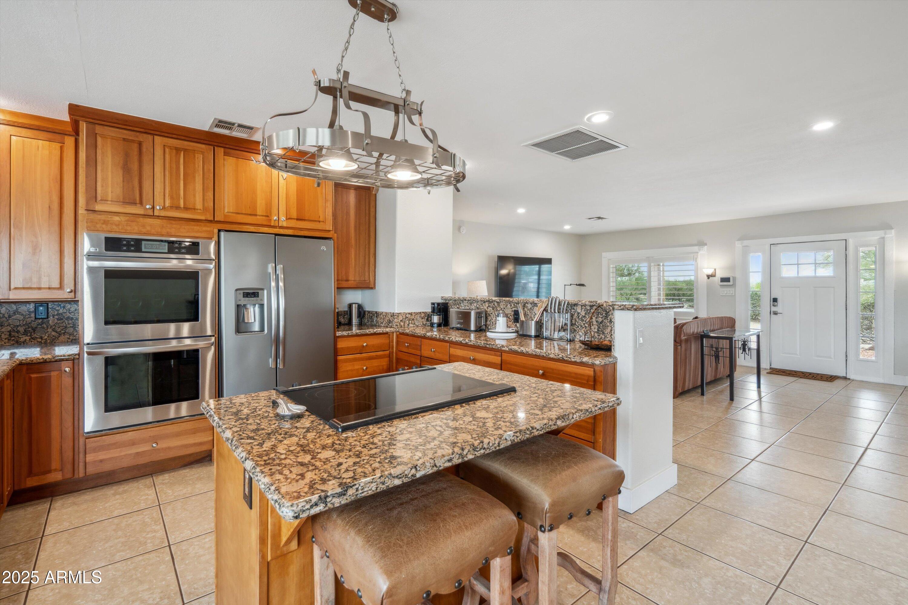 7080 East Arroyo Road Cave Creek, AZ 85331 - Photo 15 of 50 a kitchen with stainless steel appliances granite countertop a sink dishwasher stove top oven a dining table and chairs with wooden floor