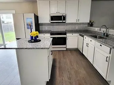 a kitchen with stainless steel appliances granite countertop a stove a sink and a granite counter tops with white cabinets