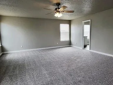 an empty room with windows and ceiling fan
