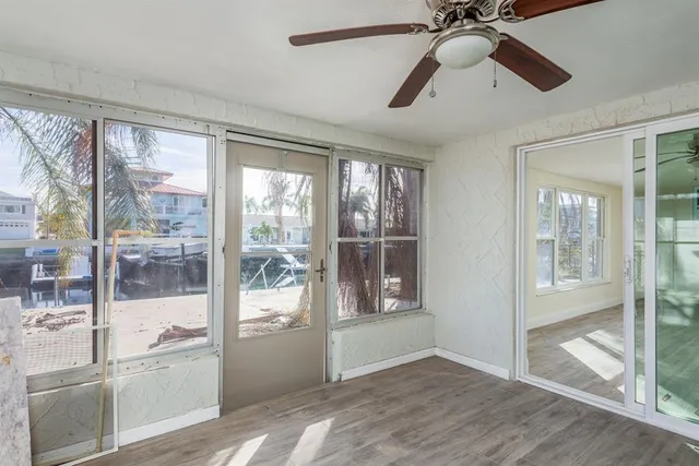 an empty room with wooden floor ceiling fan and windows