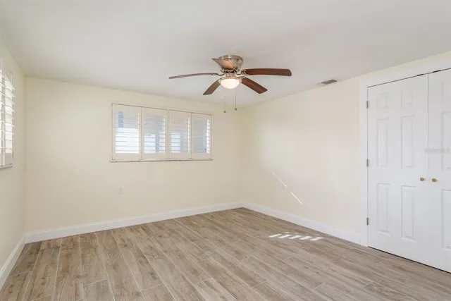 a view of an empty room with a window and wooden floor