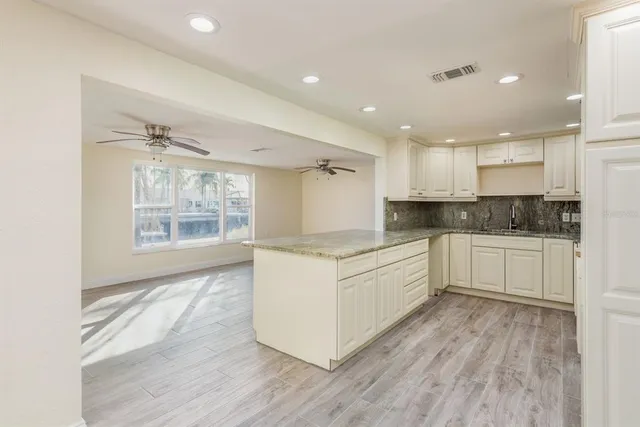 a large kitchen with stainless steel appliances granite countertop a stove a sink and white cabinets
