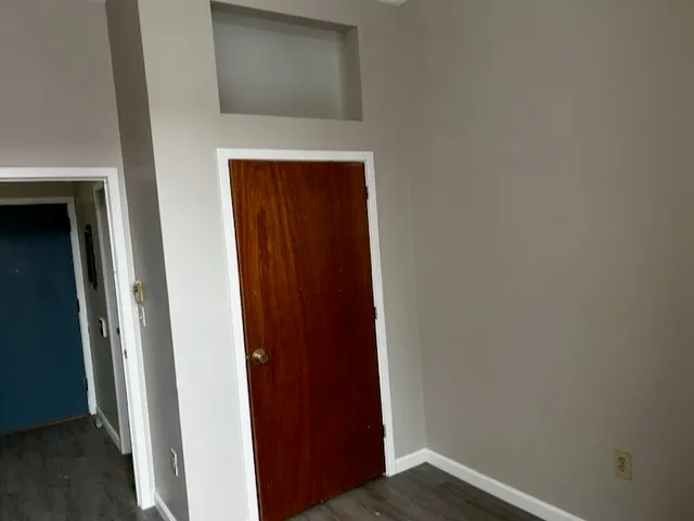 a view of an empty room with a window and wooden floor