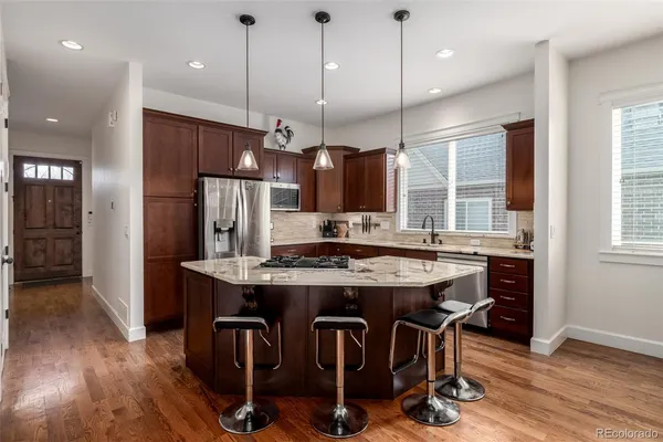 a kitchen with a table chairs refrigerator and wooden floor