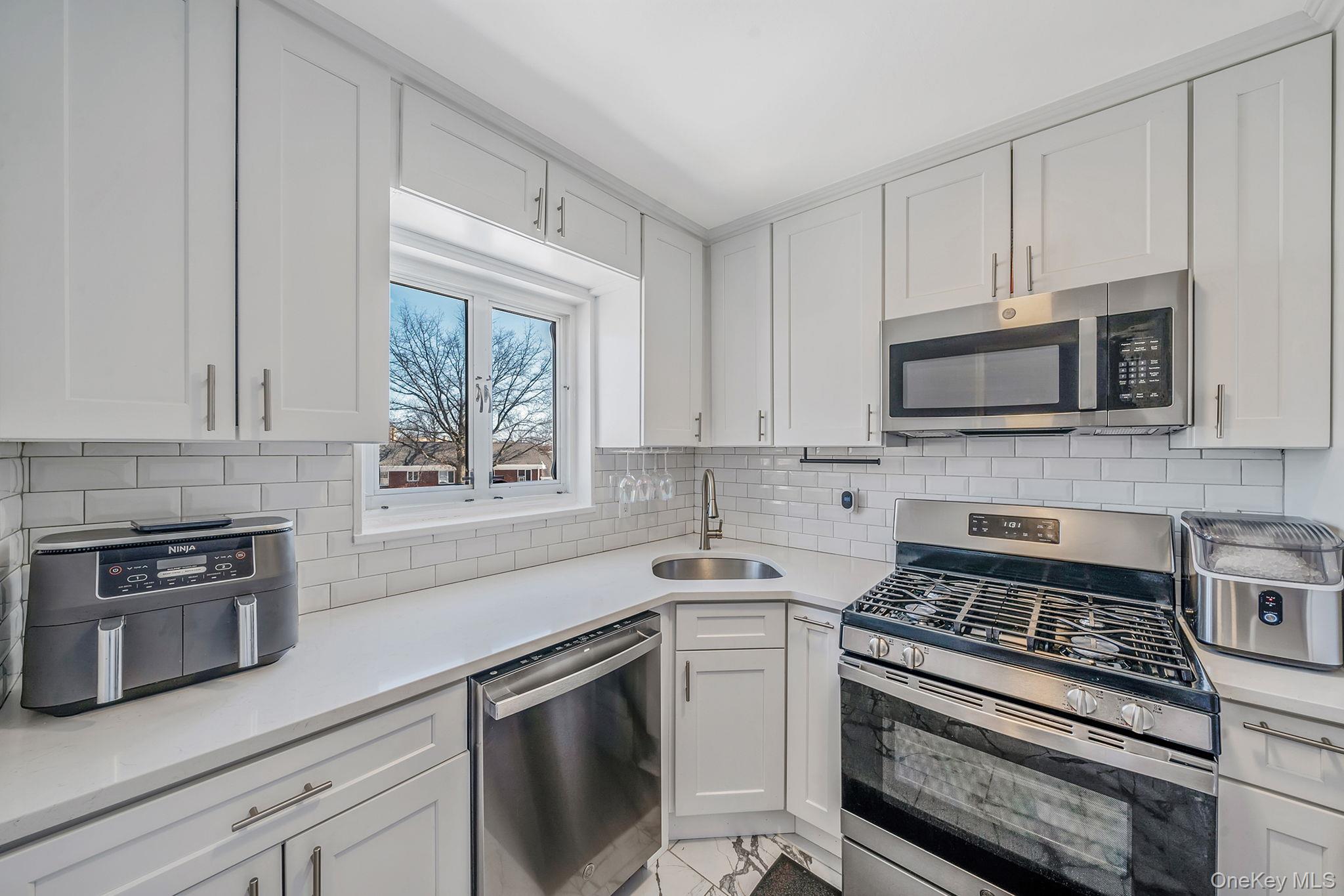 224-24 Manor Road, Unit UPPR Queens, NY 11427 - Photo 14 of 25 a kitchen with cabinets stainless steel appliances and a window