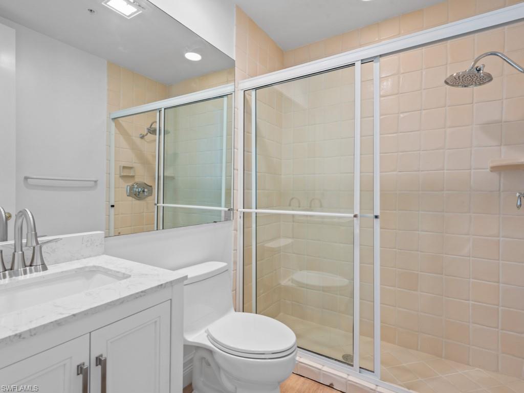 166 Colonade Circle Naples, FL 34103 - Photo 17 of 27 a bathroom with a shower a sink a toilet and a mirror