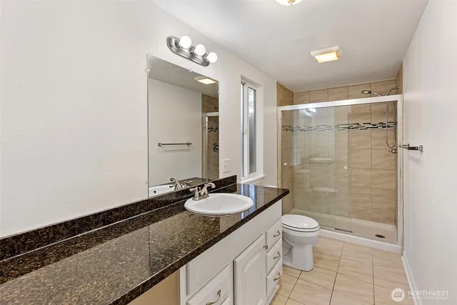 a bathroom with a granite countertop sink toilet and shower