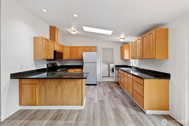 a kitchen with stainless steel appliances granite countertop a sink a stove and a wooden floors
