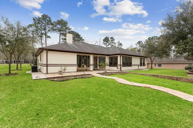 a view of a house with a big yard potted plants and large tree