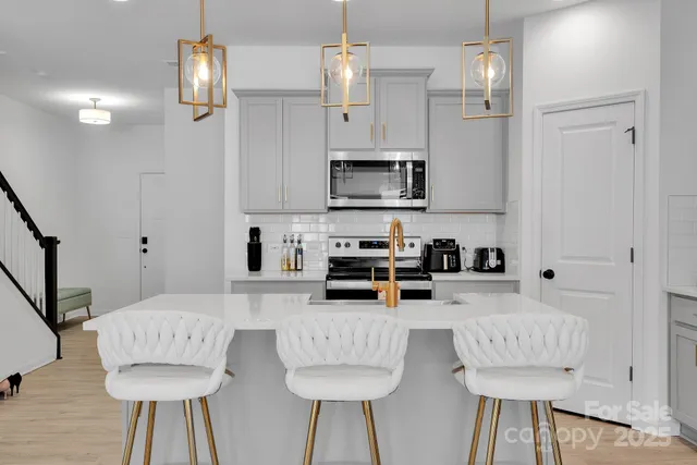 a kitchen with stainless steel appliances a stove a microwave a refrigerator and white cabinets