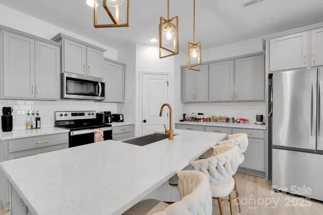 a kitchen with stainless steel appliances a stove a sink refrigerator and a microwave