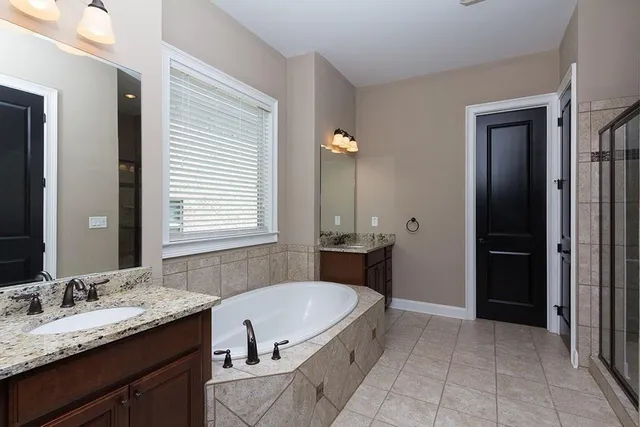 a bathroom with a granite countertop tub sink and mirror
