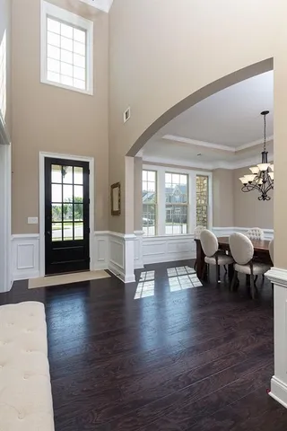 a living room with couches bookshelf and a large window with wooden floor