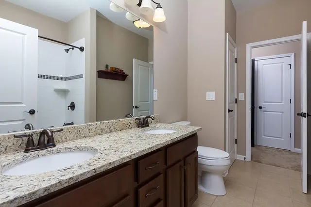 a bathroom with a granite countertop sink a toilet and shower
