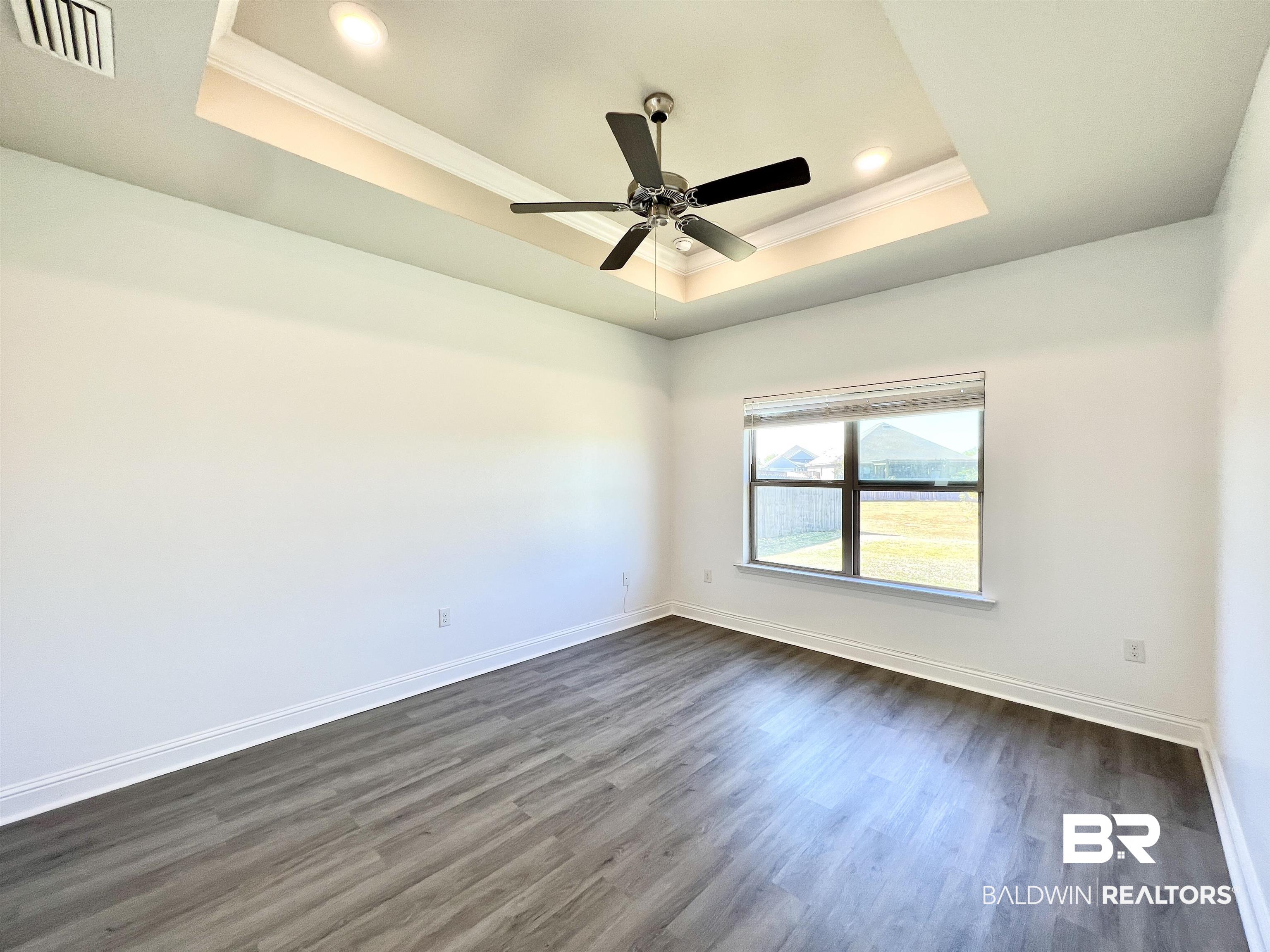 24785 Slater Mill Road Daphne, AL 36526 - Photo 24 of 46 Unfurnished room featuring ornamental molding, dark wood-type flooring, a tray ceiling, and ceiling fan