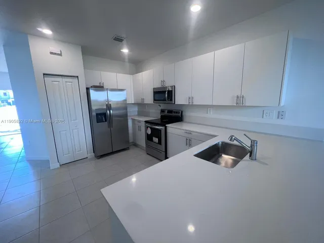a kitchen with stainless steel appliances a refrigerator a sink a stove top oven and cabinets