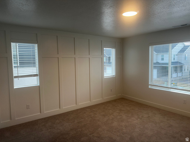 15 South Lunar Way Mapleton, UT 84664 - Photo 5 of 13 Unfurnished bedroom featuring a textured ceiling, dark carpet, and a decorative wall