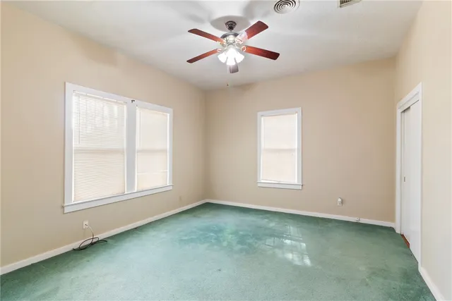 an empty room with windows and fan