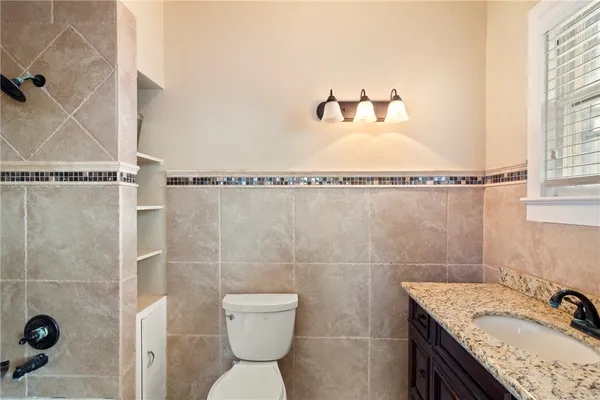 a bathroom with a granite countertop sink toilet and shower