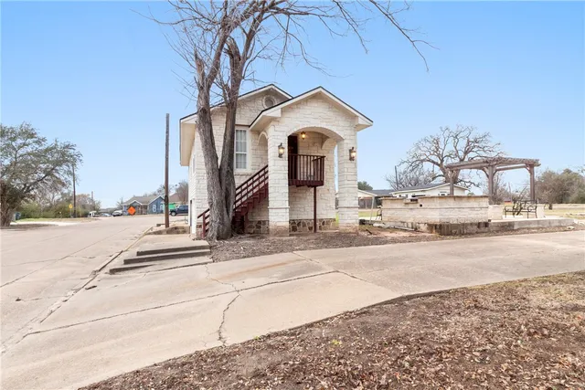 a view of a house with a yard and road