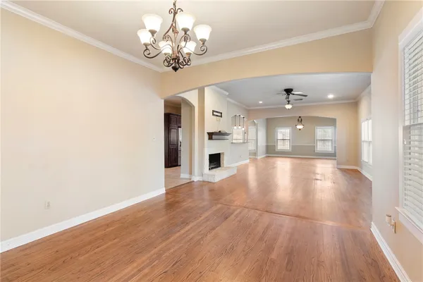 a view of an empty room with wooden floor and a kitchen