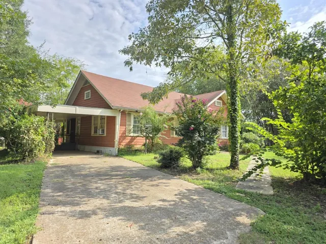 a front view of a house with a garden and yard