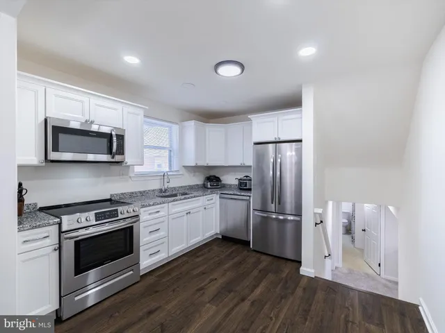 a kitchen with granite countertop a refrigerator stove and microwave