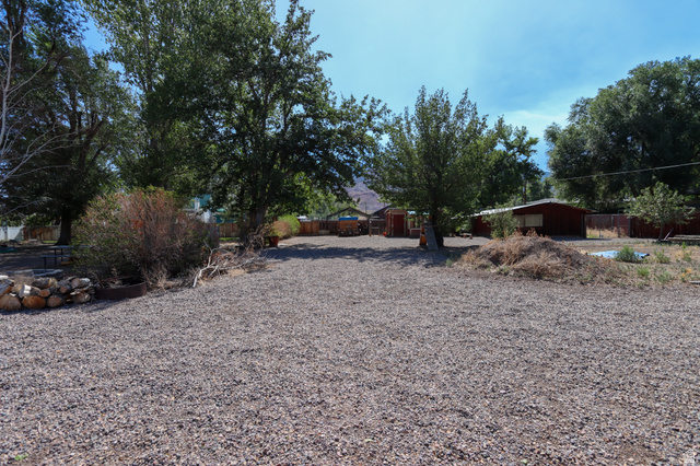 270 East 100 North Monroe, UT 84754 - Photo 48 of 65 Expansive gravel yard featuring mature trees and a dedicated fire pit area with stone and wood accents