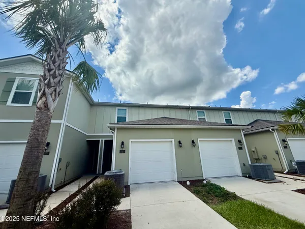 a view of a white house with a large tree and a yard