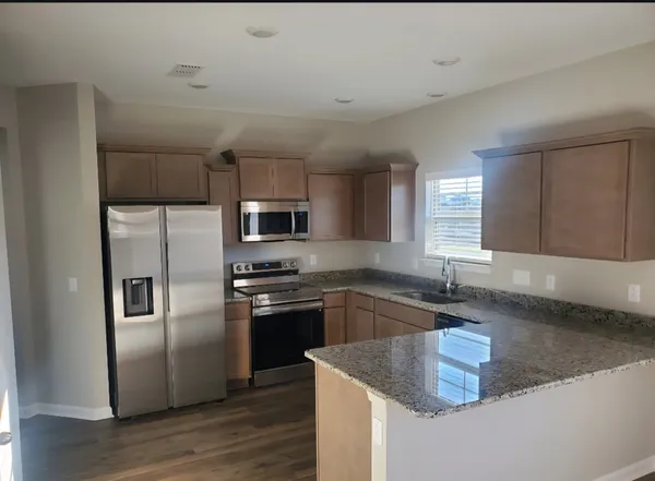 a kitchen with stainless steel appliances granite countertop a sink a stove and a refrigerator