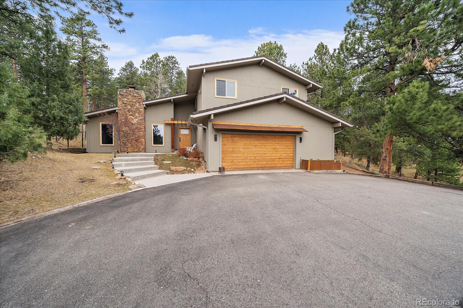 4039 Histead Way Evergreen, CO 80439 - Photo 2 of 48 a front view of a house with a yard and garage