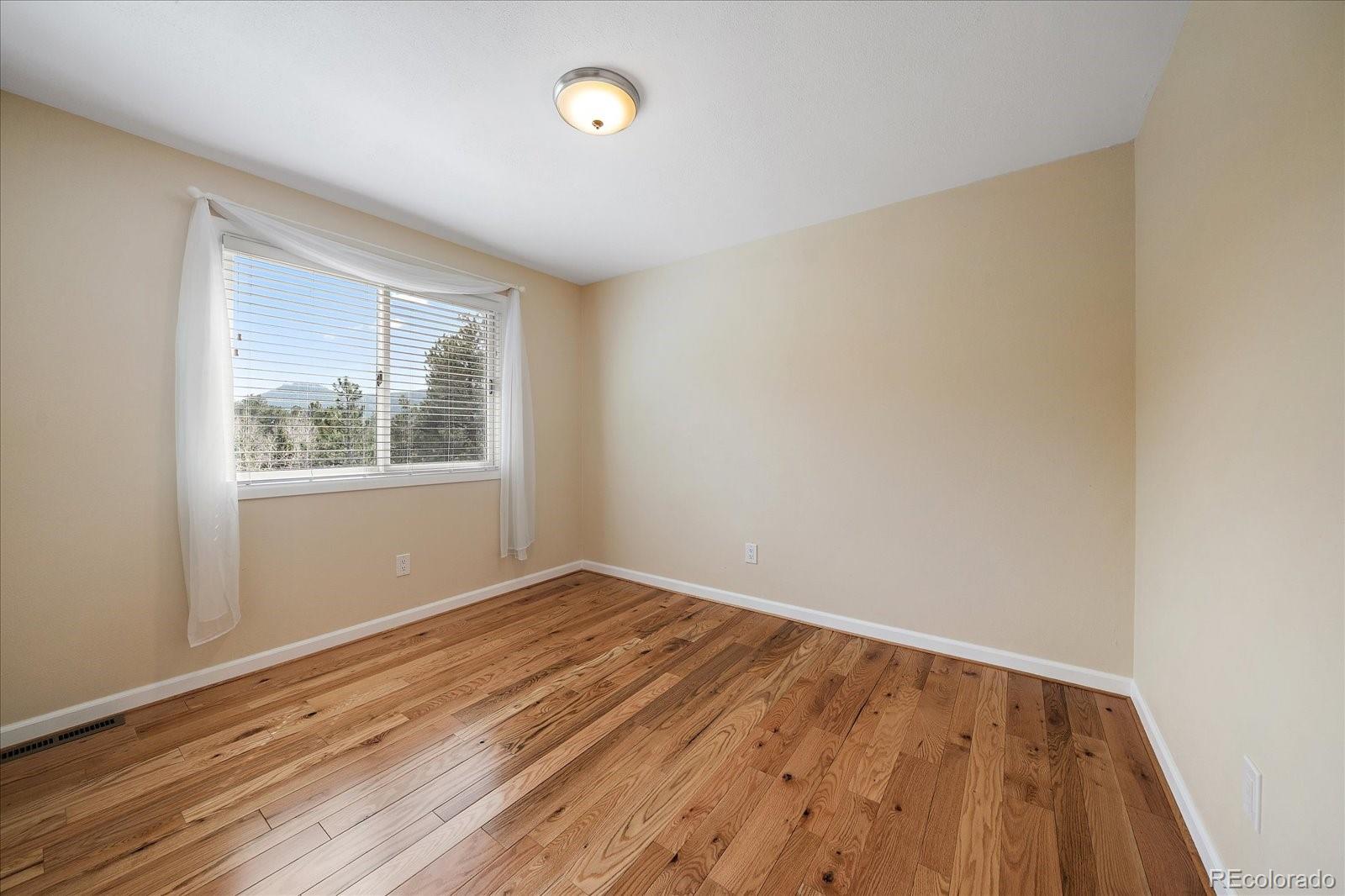 4039 Histead Way Evergreen, CO 80439 - Photo 32 of 48 an empty room with wooden floor and windows