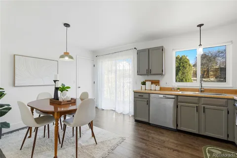 a kitchen with stainless steel appliances granite countertop wooden floor dining table chairs and white cabinets
