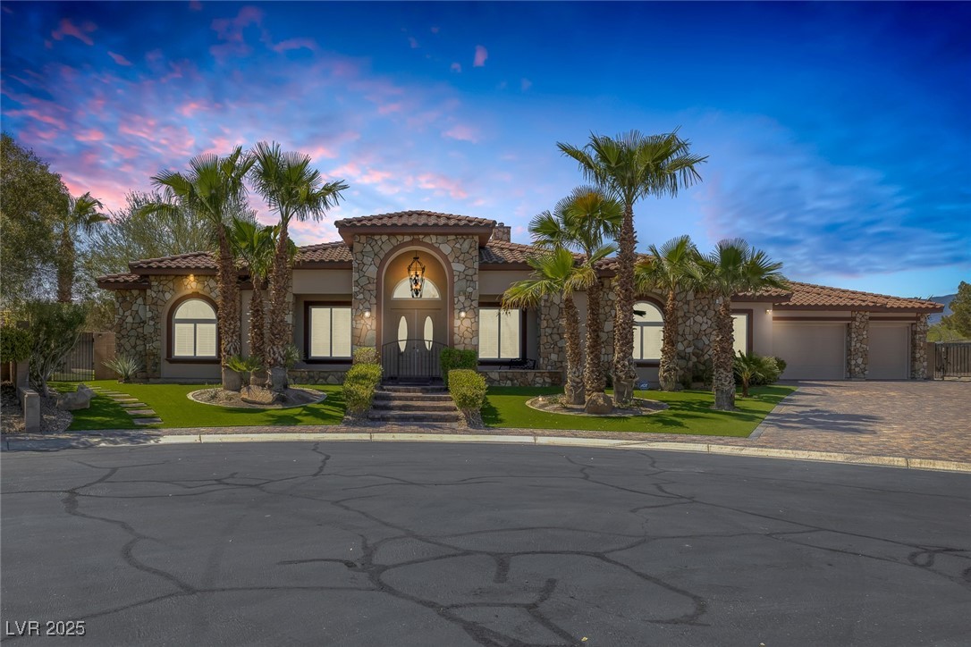7687 West Pebble Road Las Vegas, NV 89113 - Photo 1 of 79 Mediterranean / spanish house with stucco siding, stone siding, decorative driveway, an attached garage, and a tiled roof
