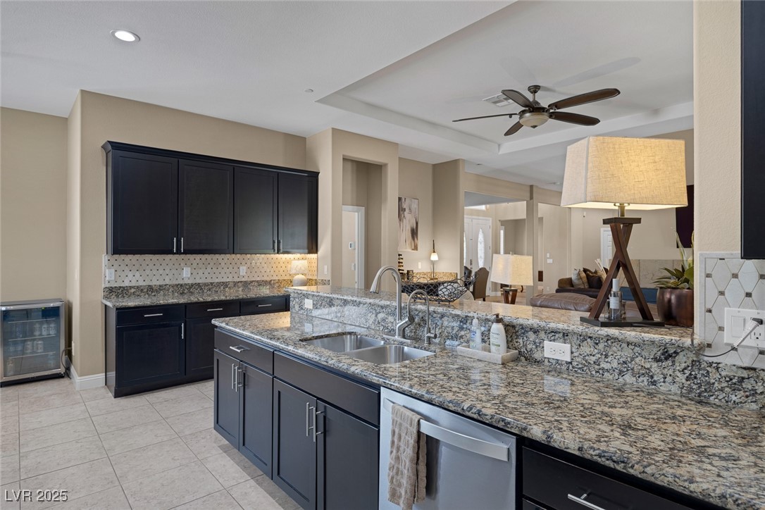 7687 West Pebble Road Las Vegas, NV 89113 - Photo 19 of 79 Kitchen featuring stone counters, a ceiling fan, decorative backsplash, dishwasher, and a sink