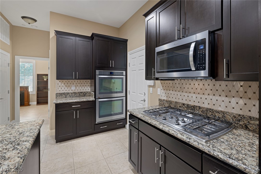 7687 West Pebble Road Las Vegas, NV 89113 - Photo 22 of 79 Kitchen with light tile patterned floors, decorative backsplash, light stone counters, and stainless steel appliances