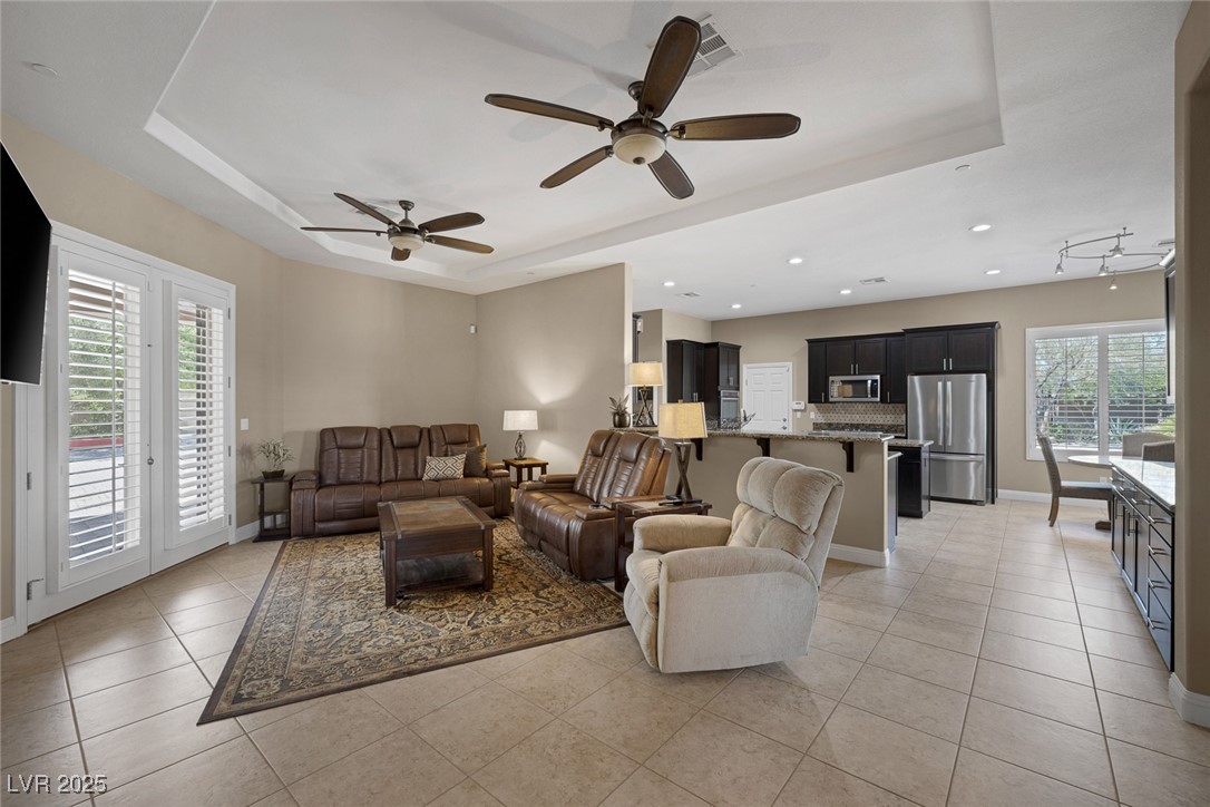 7687 West Pebble Road Las Vegas, NV 89113 - Photo 23 of 79 Living room featuring a raised ceiling, light tile patterned floors, ceiling fan, and baseboards