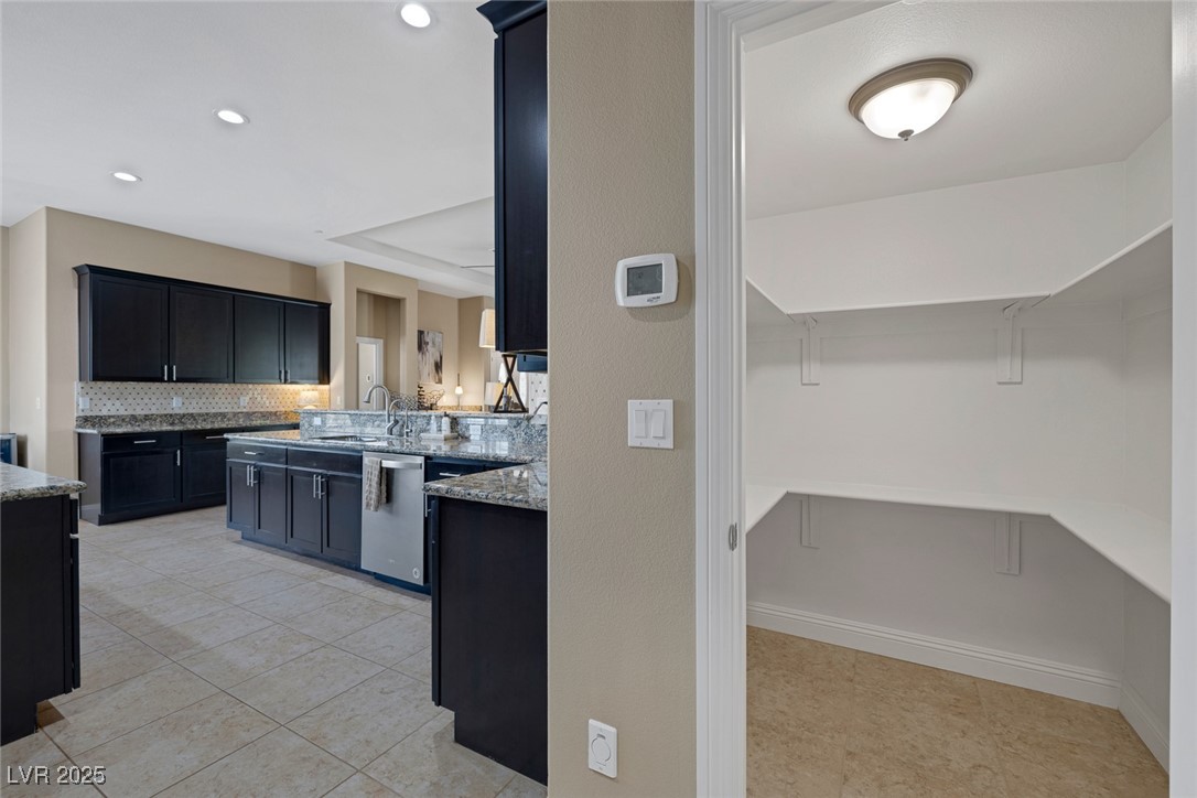 7687 West Pebble Road Las Vegas, NV 89113 - Photo 24 of 79 Kitchen with tasteful backsplash, stainless steel dishwasher, a sink, and light stone countertops